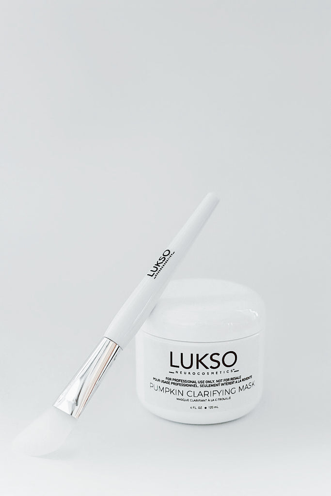 Pinceau à poile blanche antibactérien à embout métallique et blanc accoté sur un bocal de masque blanche LUKSO NeuroCosmetics 